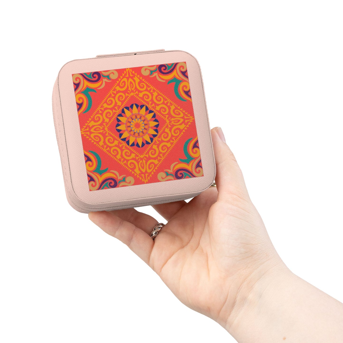 Hand holding a small square travel jewelry case with a colorful pattern on a white background