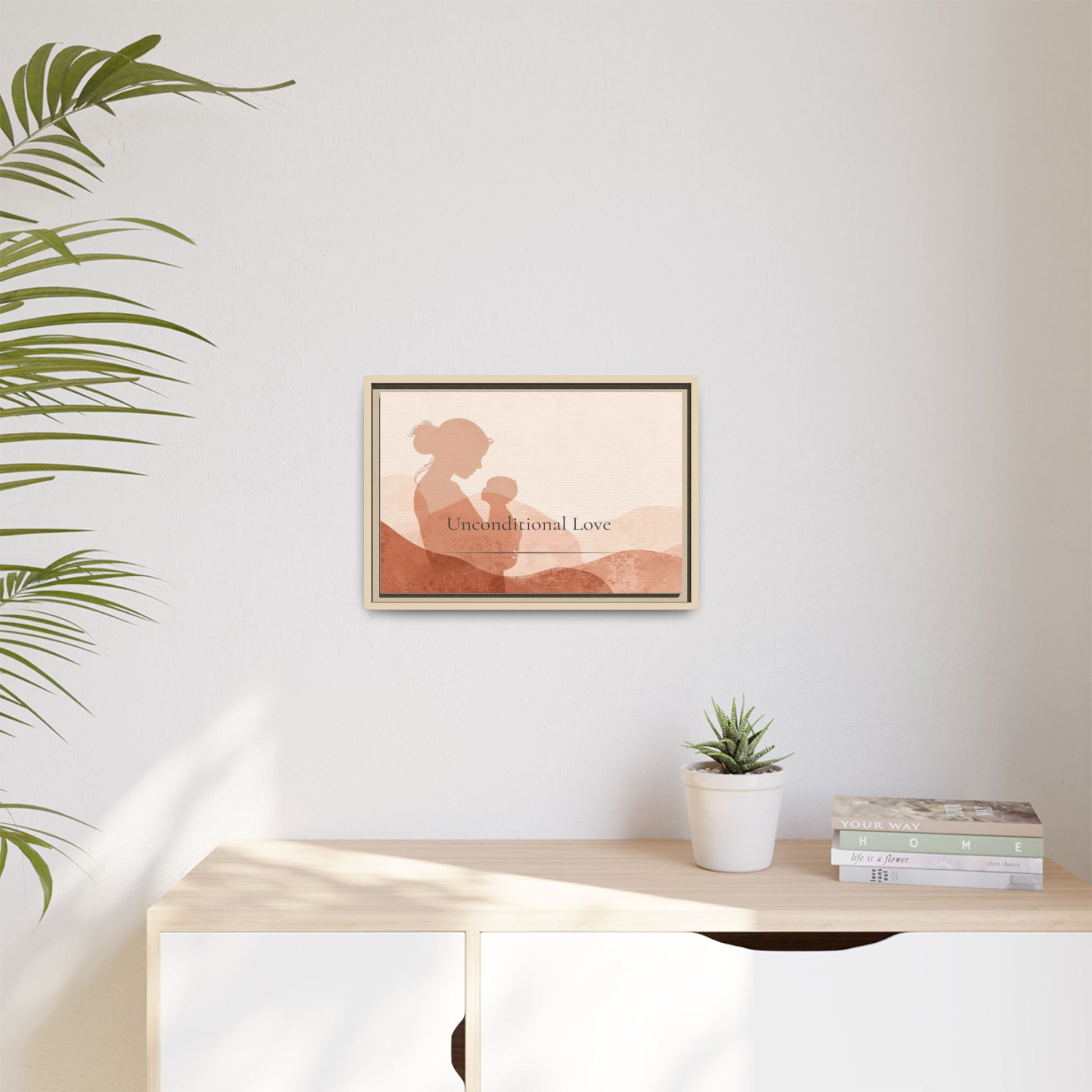 Framed artwork of a silhouette with 'Unconditional Love' text on a wall above a desk with a plant and books.