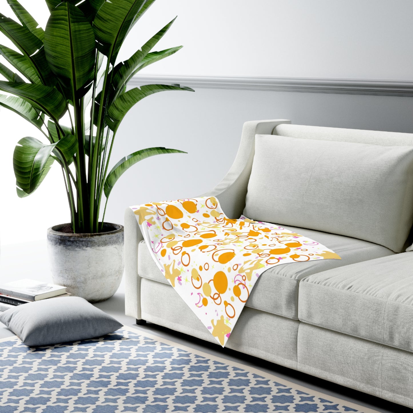 Light gray sofa with a colorful patterned blanket in a living room setting.