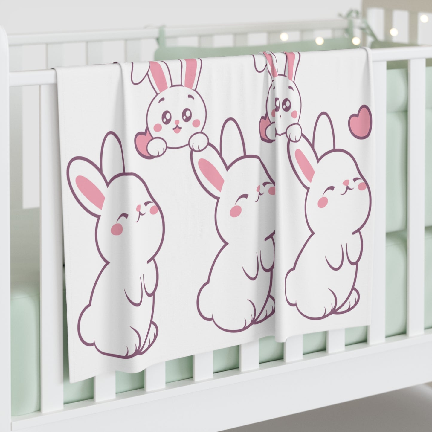 Crib with cartoon bunny blanket and pink hearts.