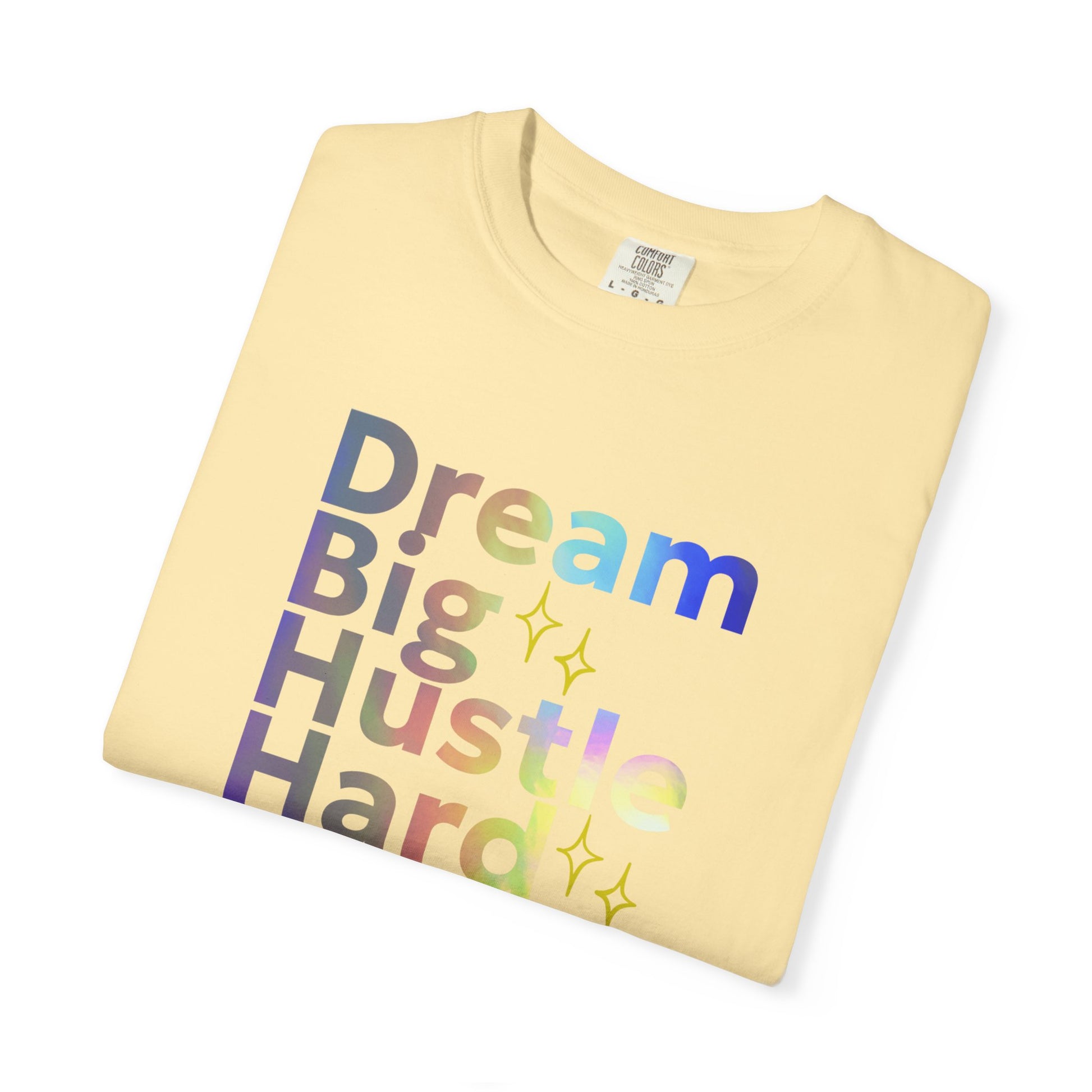 Folded yellow t-shirt with 'Dream Big Hustle Hard' text in colorful letters on a white background