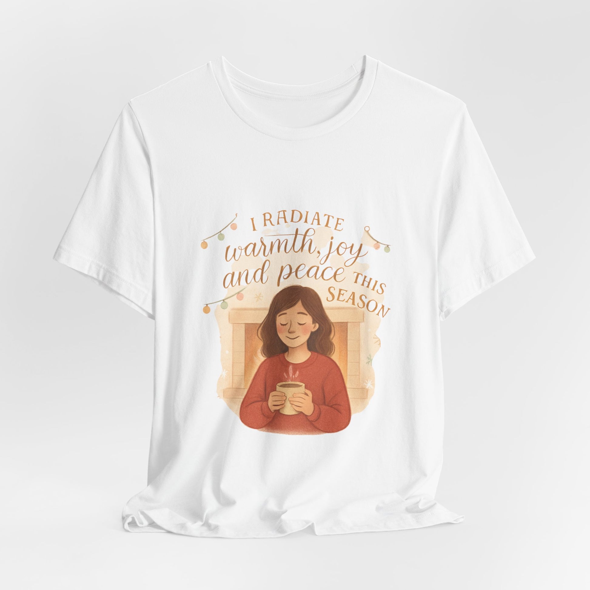 White t-shirt with a graphic of a person holding a mug and text 'I radiate warmth, joy and peace this season' on a white background.