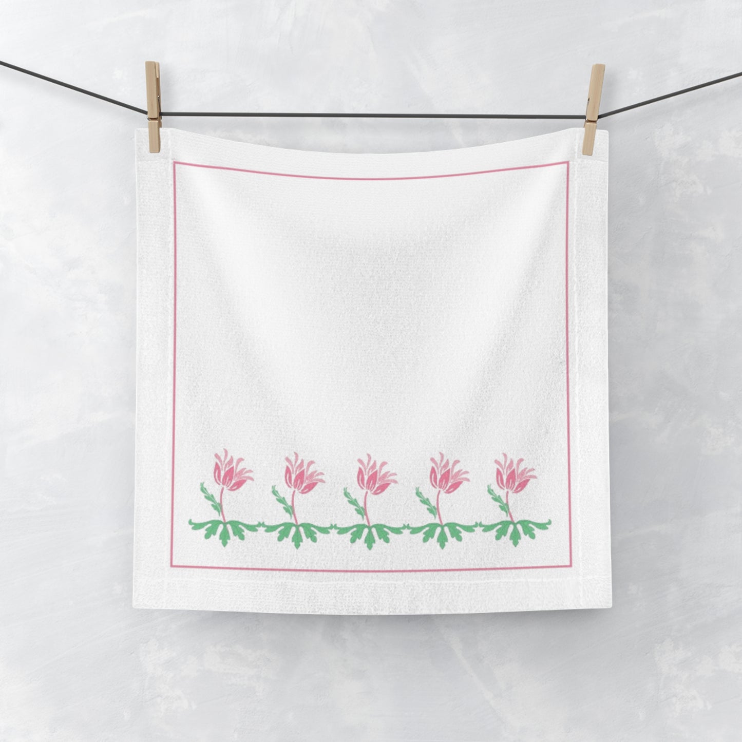 White towel with pink floral design hanging on a line.