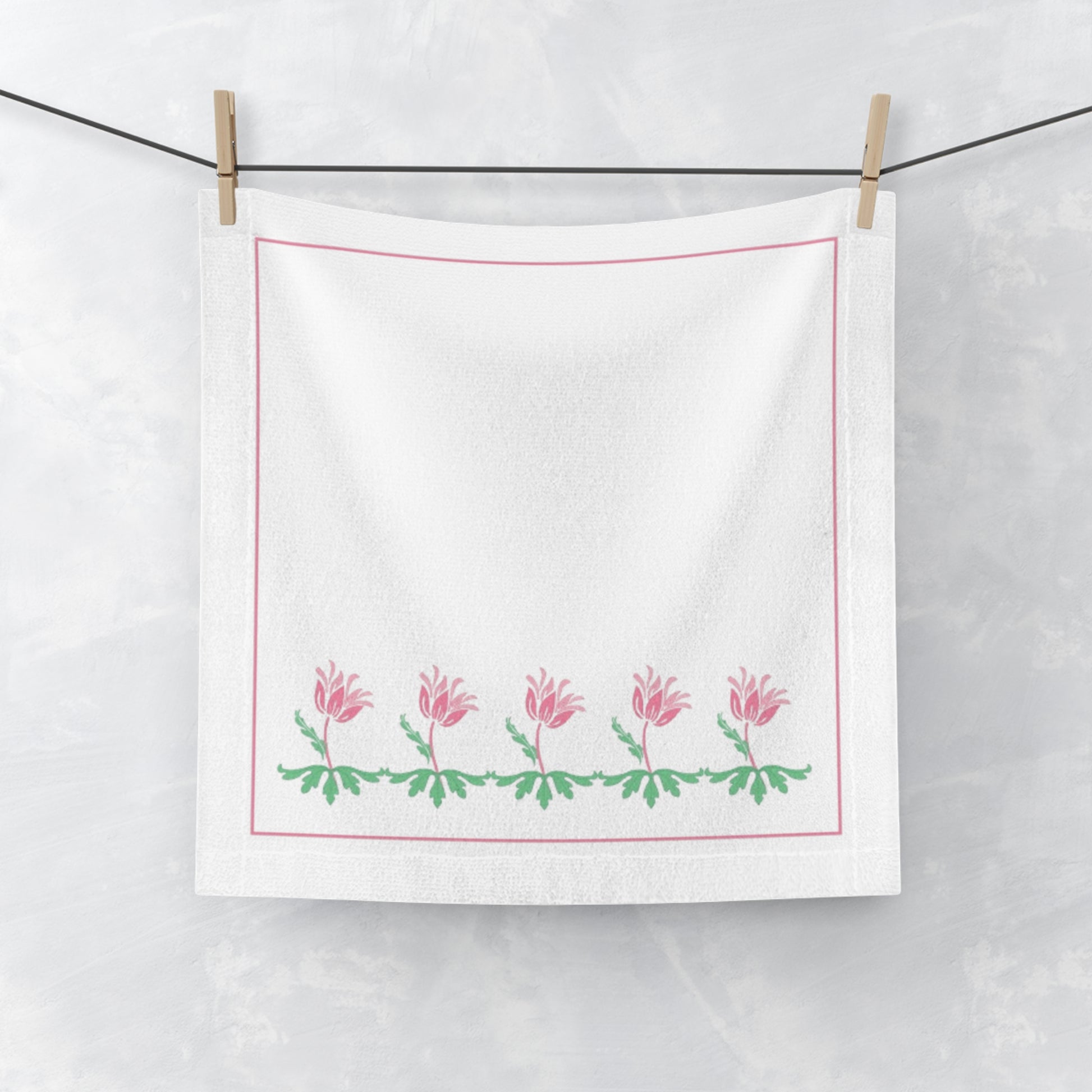 White towel with pink floral design hanging on a line.
