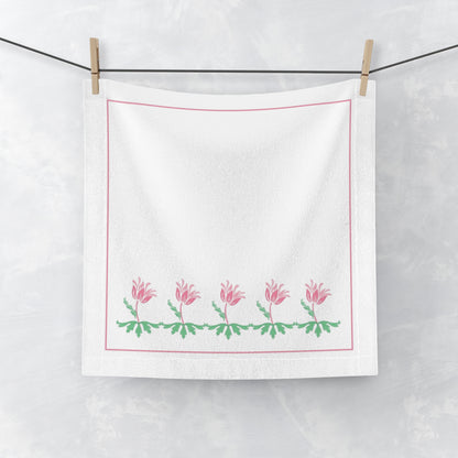 White towel with pink floral design hanging on a line.