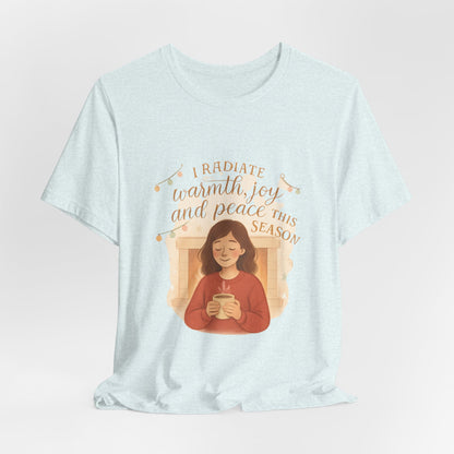 Light blue t-shirt with a graphic of a person holding a mug and text 'I radiate warmth, joy and peace this season' on a light gray background.