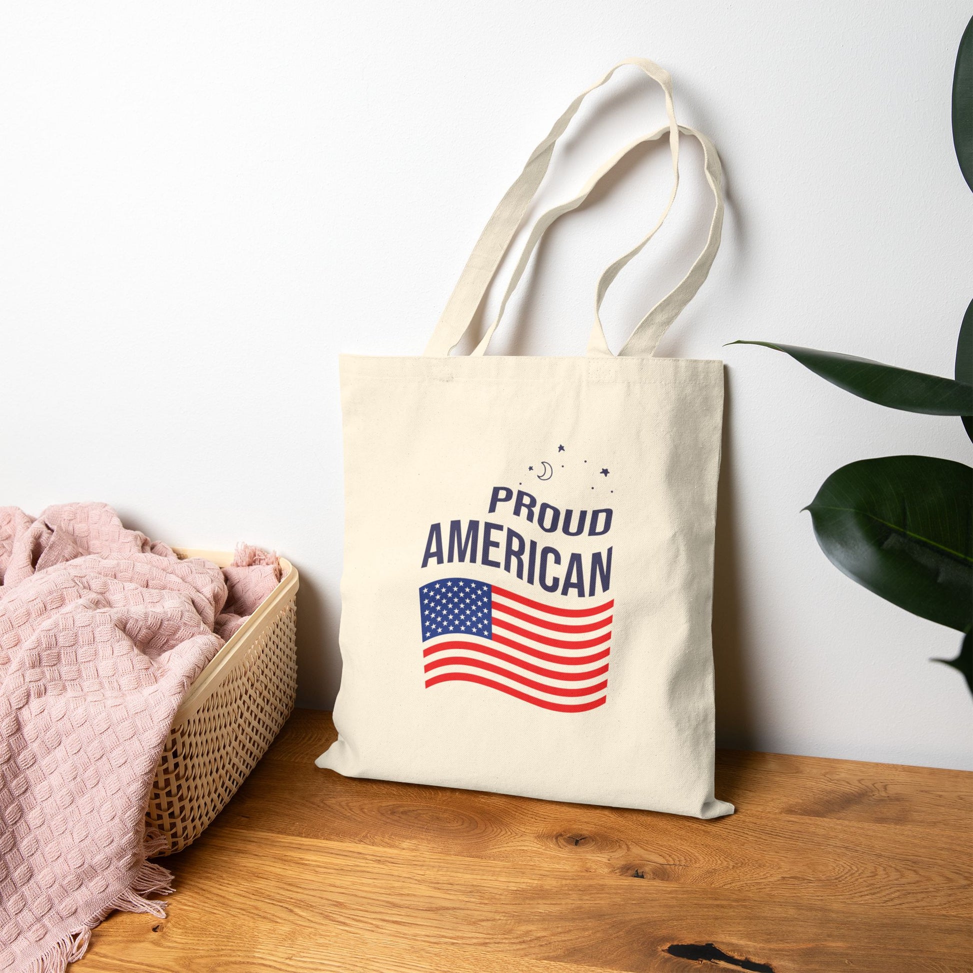 Tote bag with 'Proud American' text and flag design on a wooden surface.